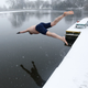A swimmer dives into the men's pond as snow falls on Hampstead Heath